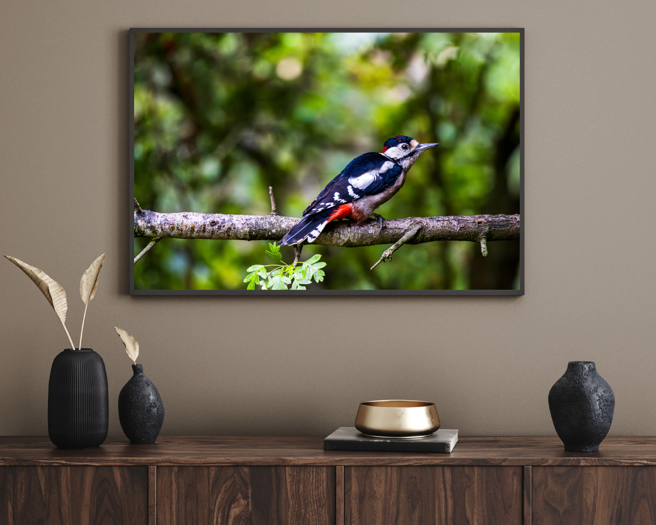 Framed picture of a bird on a branch above a wooden console table with decorative items.